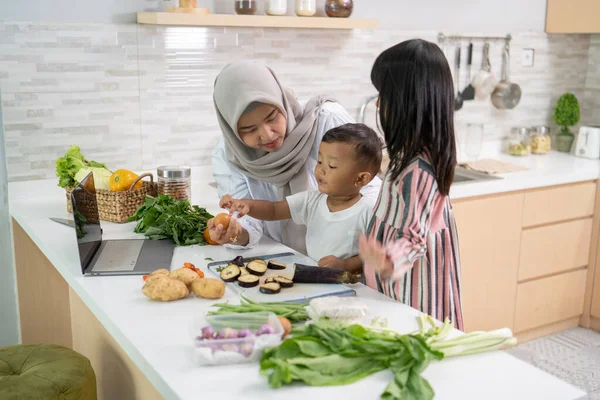 Ibu Muslim dan anak-anaknya memasak bersama di rumah mempersiapkan makan malam iftar — Stok Foto