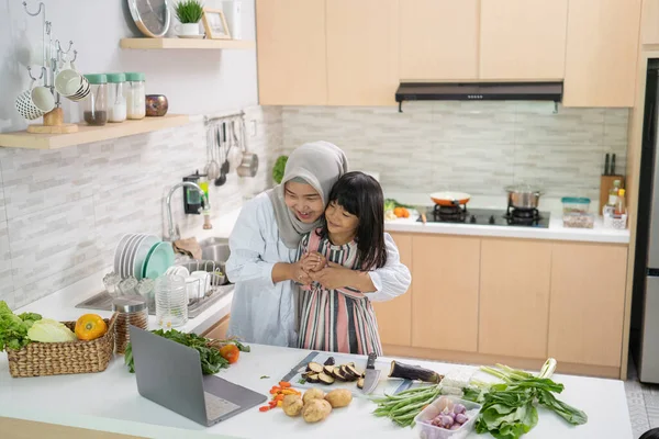 Мусульманська азіатська жінка зі своєю дочкою готує разом на кухні під час Рамадана — стокове фото