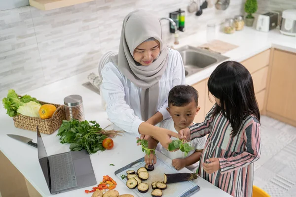 Wanita asia yang cantik dengan anak perempuan dan anak memasak makan malam selama bulan Ramadan — Stok Foto