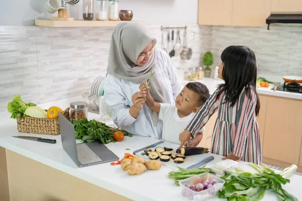 Ibu Muslim dan anak-anaknya memasak bersama di rumah mempersiapkan makan malam iftar — Stok Foto