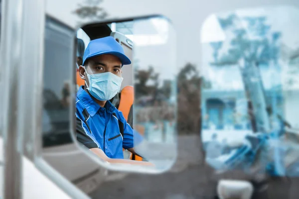 Visto da janela de um motorista masculino de uniforme e usando uma máscara olhando para a câmera — Fotografia de Stock