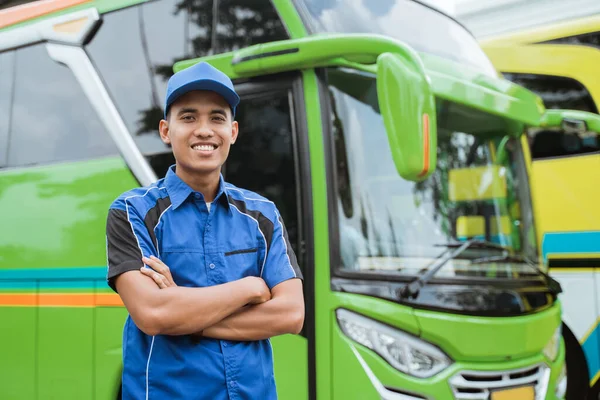 Красивый водитель автобуса в форме и шляпе улыбается скрещенными руками — стоковое фото