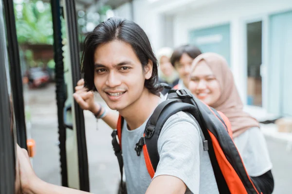 Close up of an Asian man wearing a backpack holding a door handle getting into the bus — Stock Photo, Image