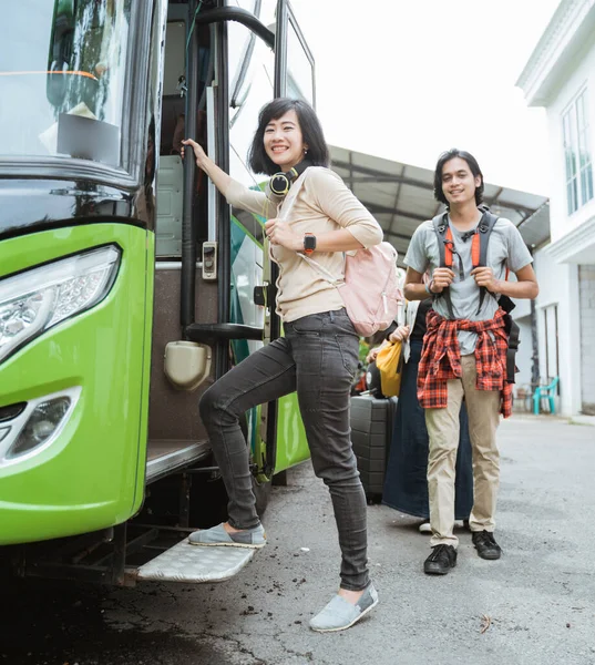 Asiatisk kvinna med hörlurar och väska ler mot kameran när klev in i bussen — Stockfoto