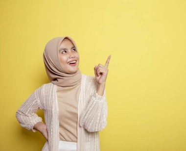 Güzel tesettürlü kadınlar gülümseyerek mutlu olurlar. Boş alanı işaret eden iyi bir fikirleri vardır.