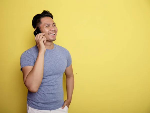 Retrato jovem feliz atender chamada enquanto segurando um telefone — Fotografia de Stock