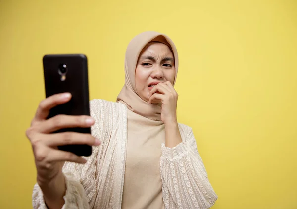 Jeune femme portant hijab avec une expression dégoûtée en regardant son téléphone — Photo