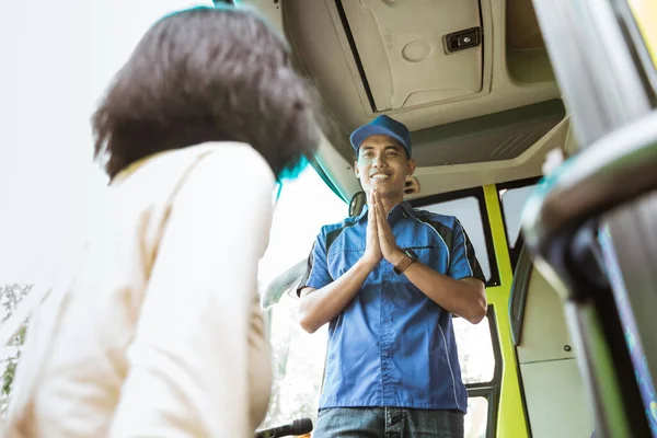 Um homem de uniforme e um chapéu com um gesto de boas-vindas a uma passageira — Fotografia de Stock