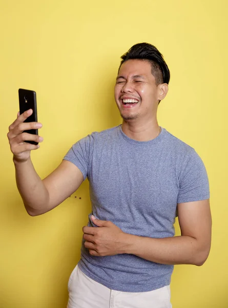 Young man laugh happy while looking at a phone — Stock Photo, Image