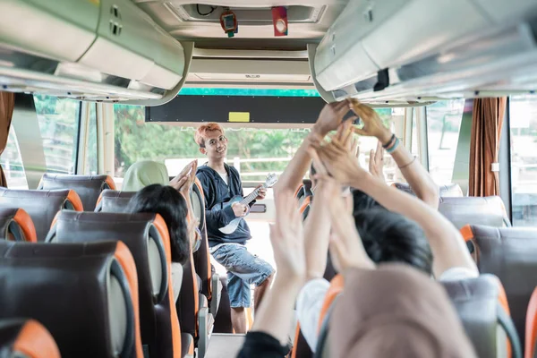 Um busker usando um instrumento musical ukulele e passageiros de ônibus cantar e bater palmas — Fotografia de Stock