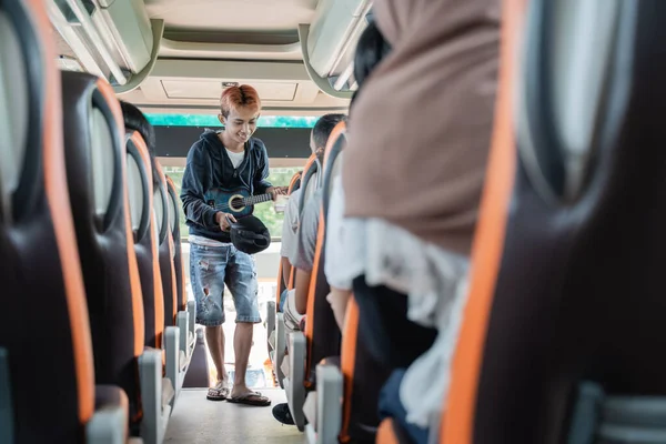 Busker használó ukulele hangszerek és sapkák pénzt kér az autóbusz utasai — Stock Fotó