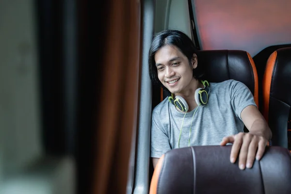 A young man in headphones sits by a window and looks out — Stock Photo, Image