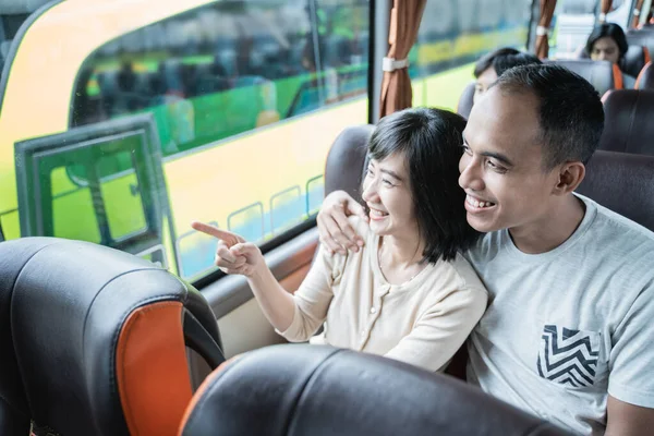 Молодий чоловік і молода жінка пальцем вказують на вікно, сидячи в автобусі — стокове фото