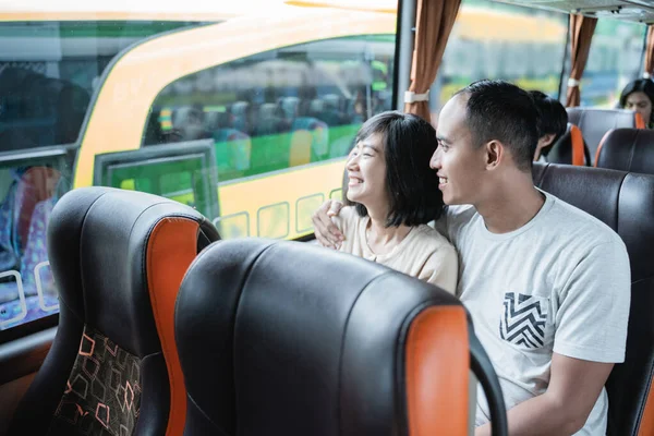 a man and woman chatting and looking out of the window while sitting on the bus
