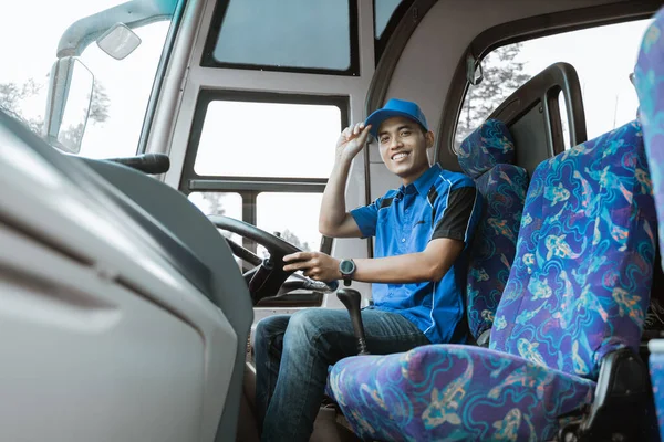 Ένας άντρας οδηγός με στολή χαμογελάει στην κάμερα καθώς κάθεται και κρατάει ένα καπέλο. — Φωτογραφία Αρχείου