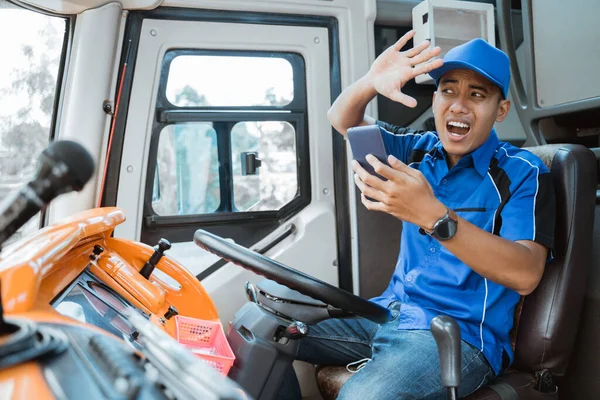 Ένας άντρας οδηγός με στολή κοιτάζει το κινητό του με μια έκφραση που συντρίβεται — Φωτογραφία Αρχείου