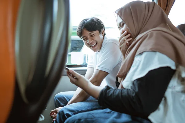 当看到手机上的视频时，亚洲穆斯林夫妇笑了 — 图库照片
