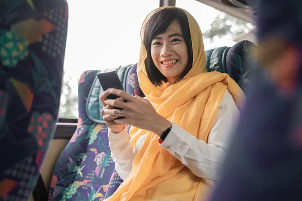 Moslim vrouw met behulp van haar mobiele telefoon tijdens het rijden op een bus — Stockfoto