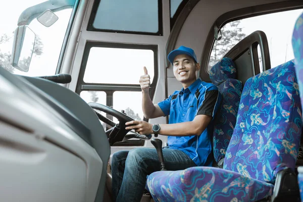 青い制服を着た男性ドライバーが親指を立ててカメラで微笑む — ストック写真