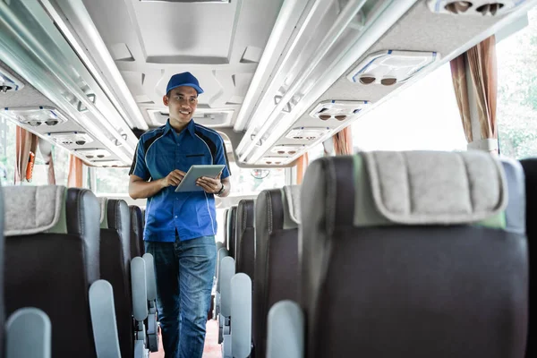 A male bus crew member uses a digital tablet while checking seats — Stock Photo, Image