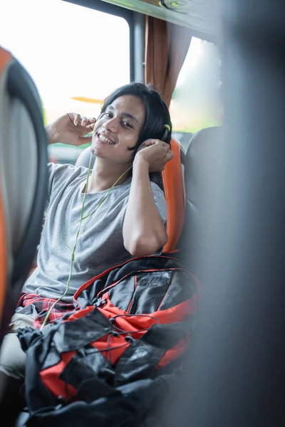 A man wearing headphones smiles while listening to music while sitting — Stock Photo, Image