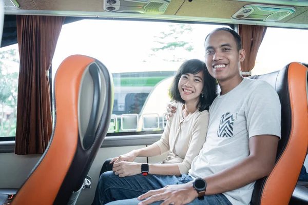 Młody mężczyzna i młoda kobieta uśmiechają się, gdy siedzą obok siebie na siedzeniu autobusu — Zdjęcie stockowe