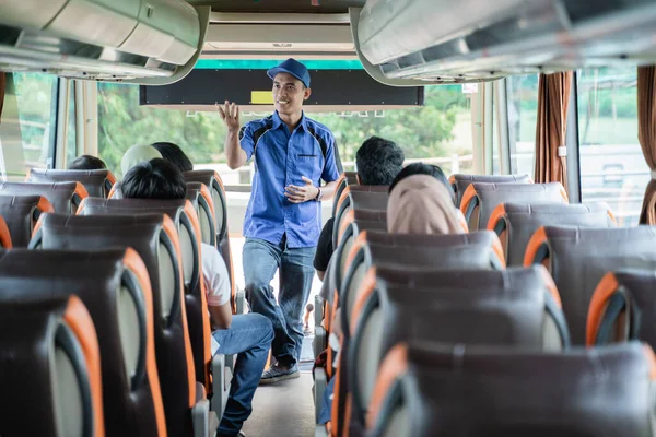 A bus crew in uniform and a hat briefs the passengers