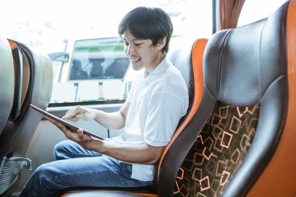 a young asian man using a tablet while sitting