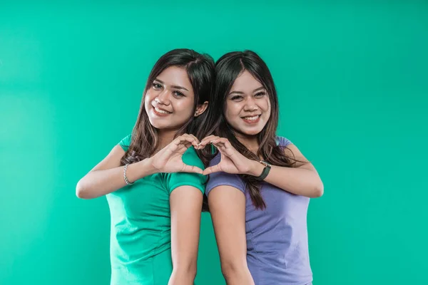 Mooie tweelingzussen tonen een hart uit hun handen — Stockfoto
