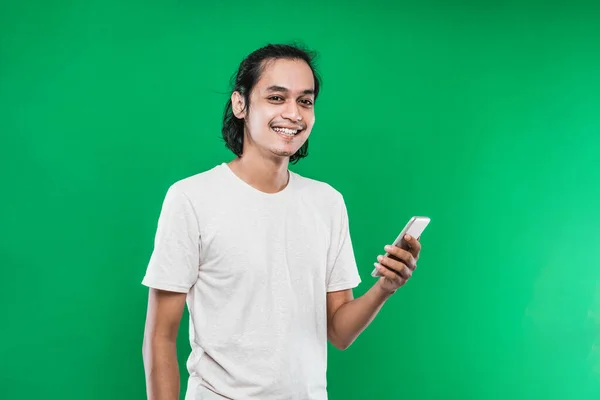 Bonito ásia homem segurando handphone com felicidade sorriso expressão enquanto olhando para o câmara — Fotografia de Stock