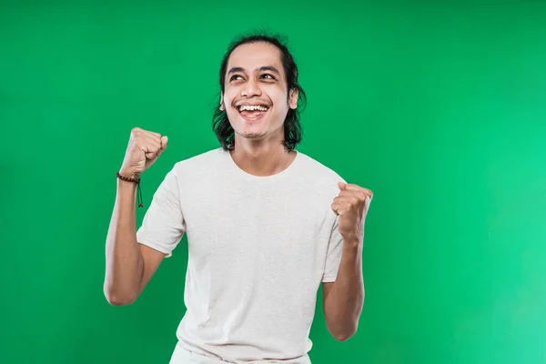 Jovem bonito expressando felicidade com apertado em punhos e levantou duas mãos — Fotografia de Stock