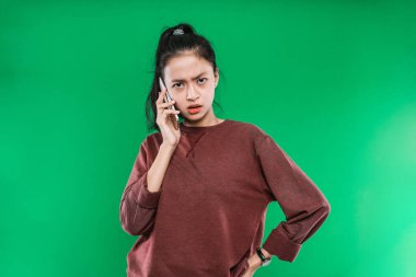 Asyalı güzel bir kadın telefonda sinirli bir ifadeyle konuşuyor.