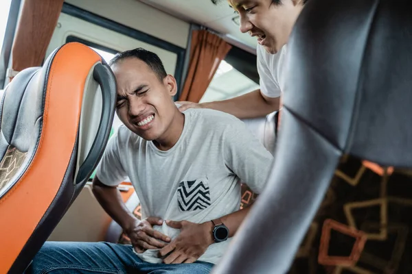 A man with a stomachache and his friend helped while sitting on a bus seat — Stock Photo, Image