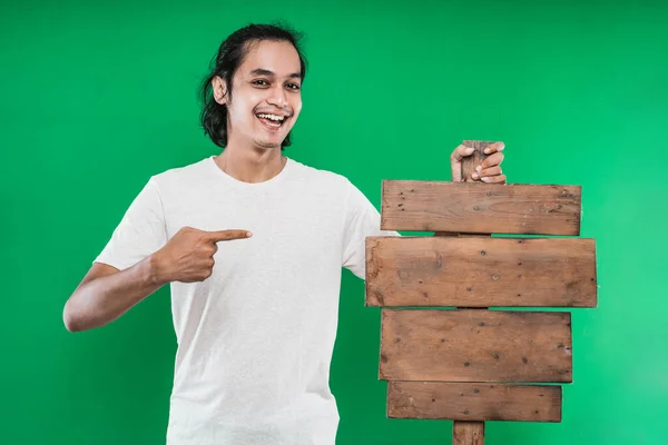 Asiatique homme pointant et présentant quelque chose planche en bois blanc à la caméra — Photo