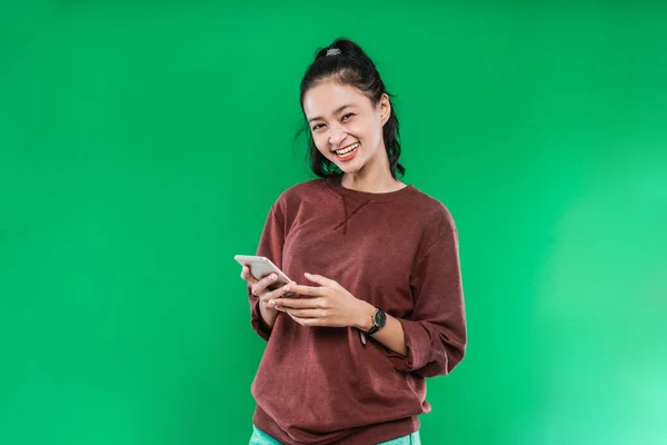 예쁜 아시아인 소녀가 카메라를 보면서 핸드폰을 들고 귀엽게 웃는 모습 — 스톡 사진