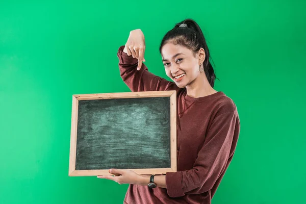 Mladá žena drží a ukazuje na dno na prázdné tabuli s úsměvem štěstí — Stock fotografie