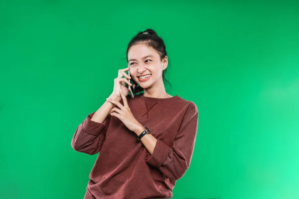 Belle jeune femme asiatique parle au téléphone souriant faiblement avec quelqu'un tout en regardant à côté — Photo