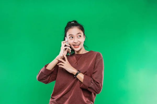 Красива дівчина з Азії розмовляє по телефону ледь посміхаючись з кимось, дивлячись вгору. — стокове фото