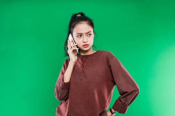 Schöne junge Asiatin telefoniert, während sie mit wütender Miene daneben schaut — Stockfoto