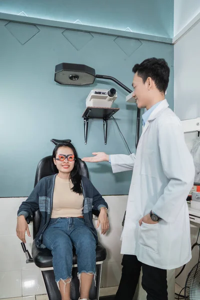 Egy férfi orvos elmagyarázza egy női betegnek a szemészeti vizsgálat folyamatát — Stock Fotó