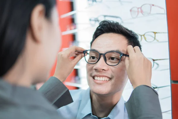 Um assistente de loja de senhora coloca novos óculos para um cliente masculino — Fotografia de Stock