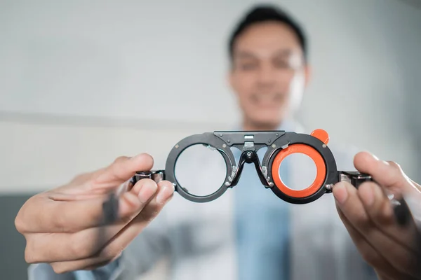 Um médico do sexo masculino segurando uma ajuda de medição de teste ocular em uma clínica ocular — Fotografia de Stock