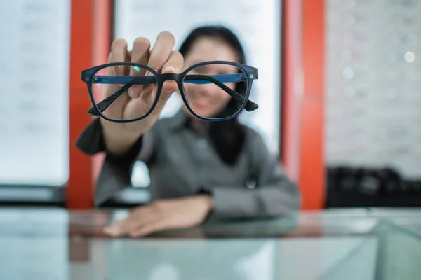 Uma mulher segura os óculos de escolha que ela escolhe — Fotografia de Stock