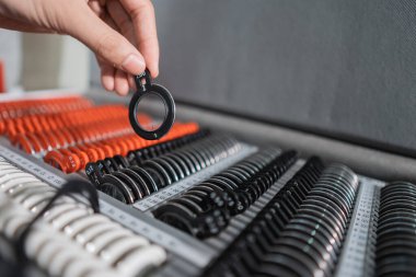 Bir göz doktorunun eli, içinde lenslerin bulunduğu bir kutuda test gözlüğü merceği göstergesi alıyor.