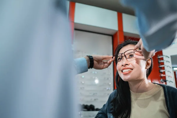 Une main d'employé aide à mettre une paire de lunettes qu'une femme qui a fait un examen de la vue a choisi — Photo