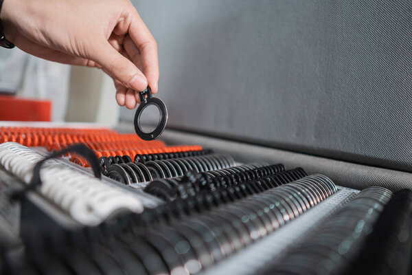 an eye doctors hand is taking a test glasses lens gauge in a box containing a set of lenses