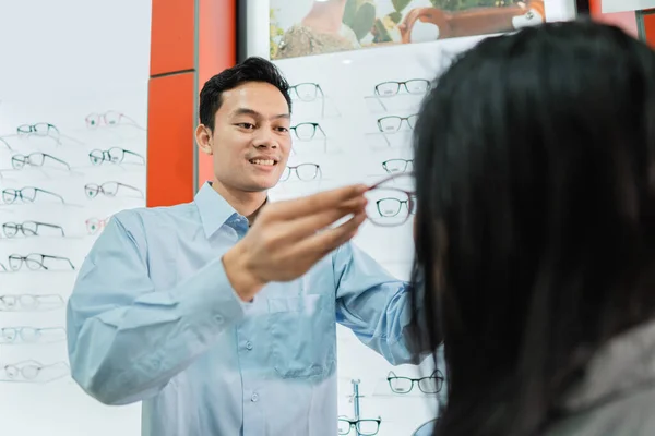 Un assistente di negozio maschile serve e veste una cliente donna — Foto Stock