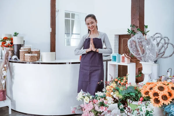 Jong vrouwelijk bloemist dragen schort staan in front office glimlachen kijken naar de camera. — Stockfoto