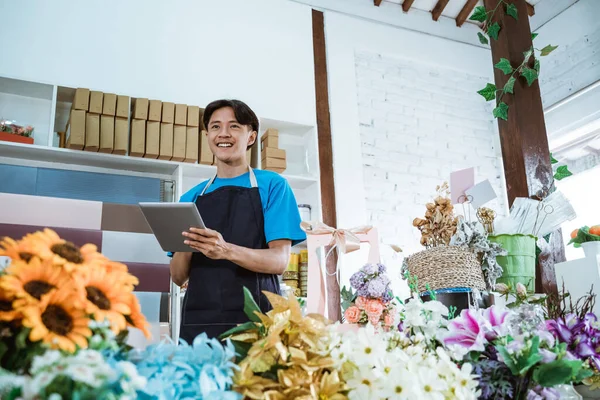 Boldog fiatal férfi vállalkozó dolgozik virágüzlet visel kötény mosolygós — Stock Fotó