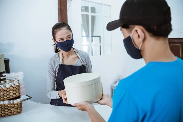 Lächelnde junge Ladenbesitzerin, die ein Paket erhält — Stockfoto